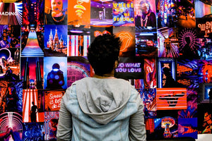 guy looking at a wall with trippy neon posters collage