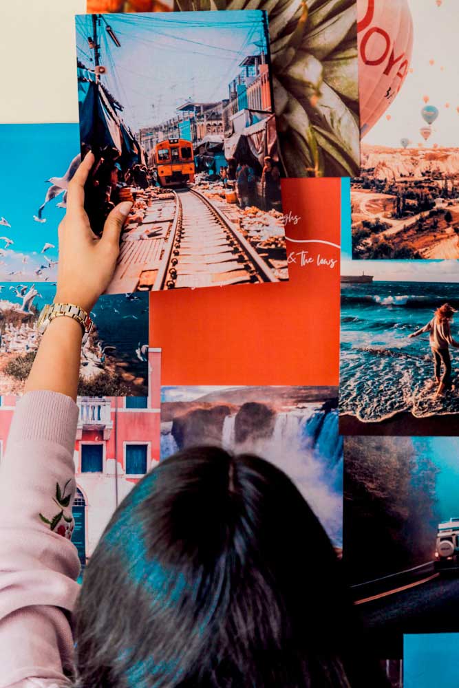 Girl putting up travel posters on a wall